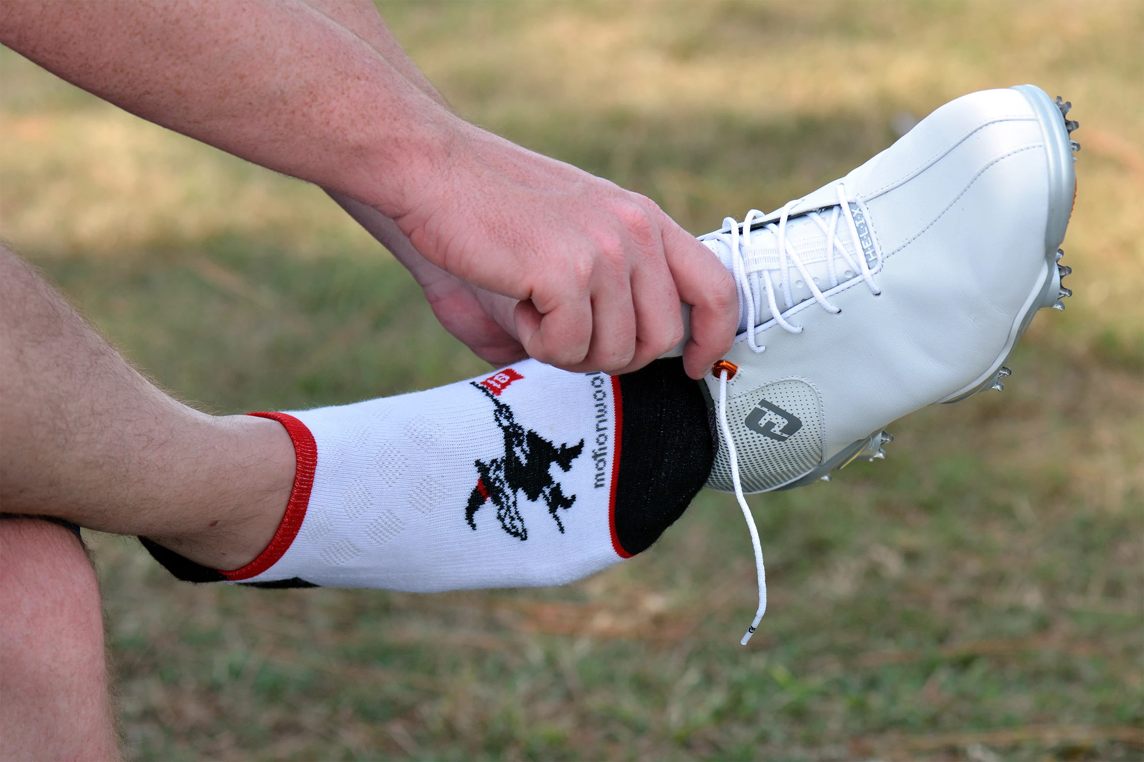 A black, white and red motionwool sock with a witch riding a broom as the design
